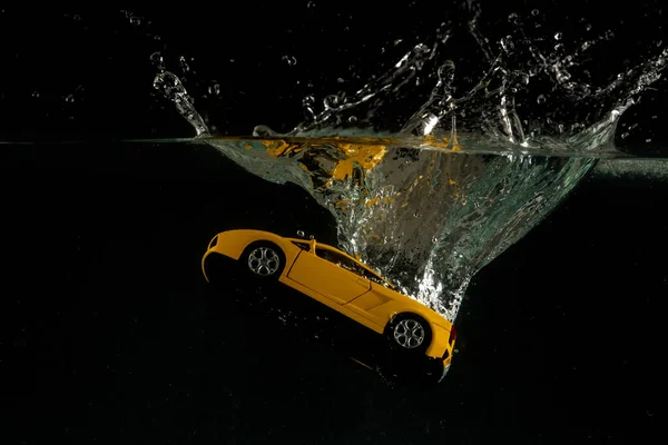 Жовтий мініатюрний іграшковий автомобіль скинув бризки і потонув на воді — стокове фото