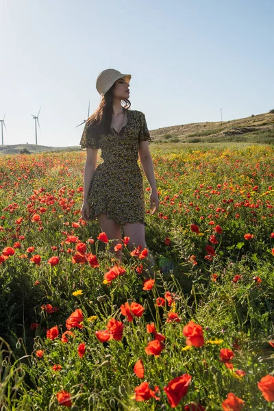 Attractive woman wearing hat posing outdoor in poppy field in spring. Freedom outdoors, springtime — Stok fotoğraf