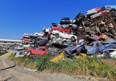 Pile of various scrap cars and other metals on a junk yard field ready recycling industry. Environmental pollution