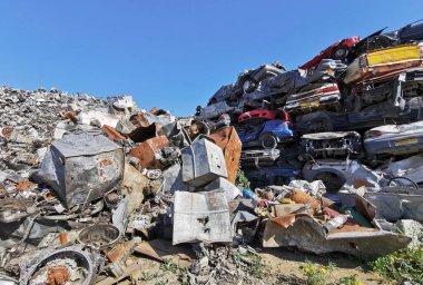 Pile of various scrap cars and other metals on a junk yard field ready recycling industry. Environmental pollution