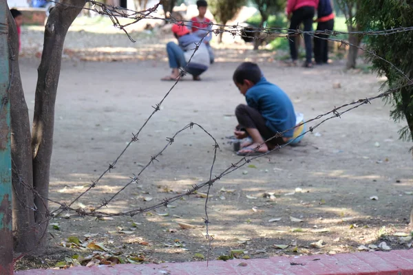 Crianças Não Reconhecidas Brincando Playground Atrás Uma Cerca Metal Farpado — Fotografia de Stock