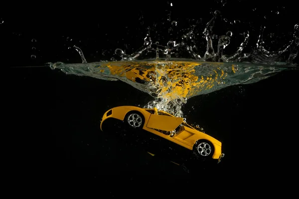 黄色のミニチュアのおもちゃの車が飛び散って水に沈む — ストック写真