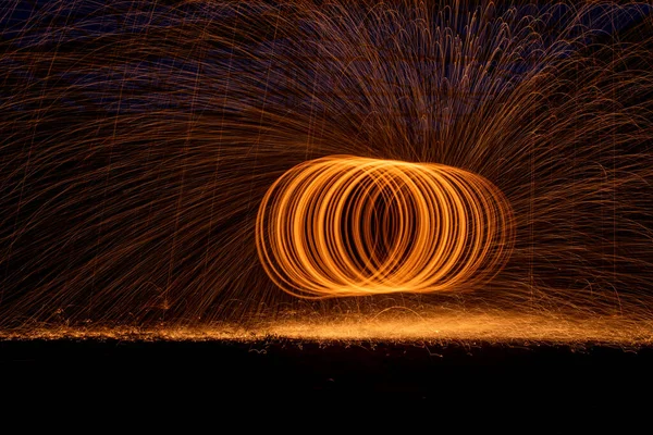 Orange circle moving bright fire light trails on black background.