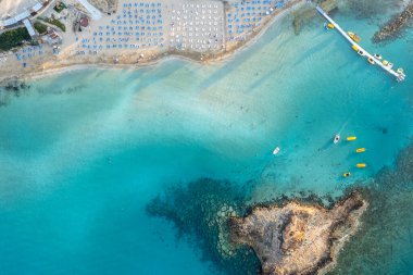 Kıbrıs Rum Kesimi 'nin İncir Ağacı Koyu sahil Protaras' ında arka arkaya plaj şemsiyeleri. Yaz tatili tatil beldesi altın kum