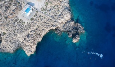 Drone aerial photograph of Cape Greco peninsula with Agioi Anargyroi christian church on the rocks. Turquoise ocean water
