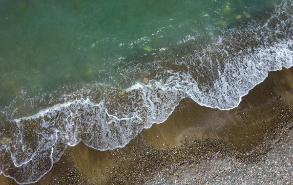 Aerial view of a beach with ocean wind waves splashing on the coast