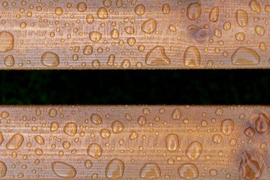 Yağmurdan düşen parlak su damlaları ve ıslak ahşap kalaslarla kaplı sönük ahşap dokunun yatay arka planı