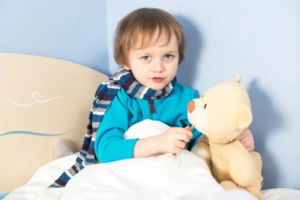 Pequeno menino doente verificando ursinho de pelúcia — Fotografia de Stock