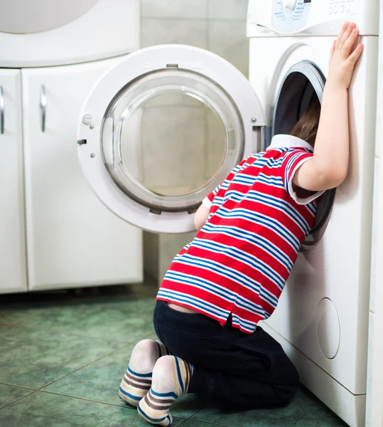 Piccolo bambino pericolosamente mettendo la testa nel tamburo della lavatrice — Foto Stock