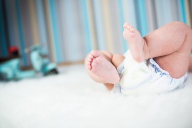 Newborn baby in diaper lying on plush blanket clipart