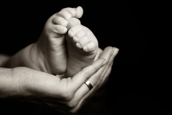 Mother gently holding her baby foot Royalty Free Stock Images