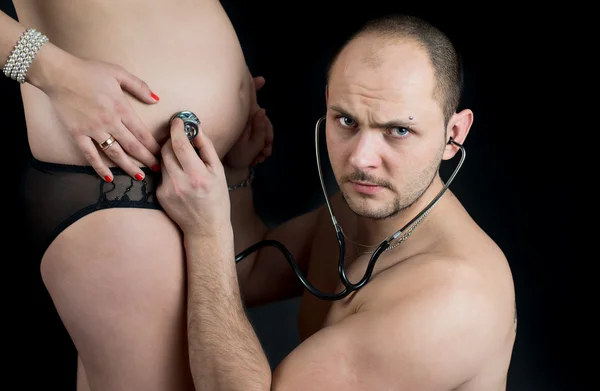 Vater hört Schwangerschaftsbauch seiner Frau mit Stetheskop — Stockfoto