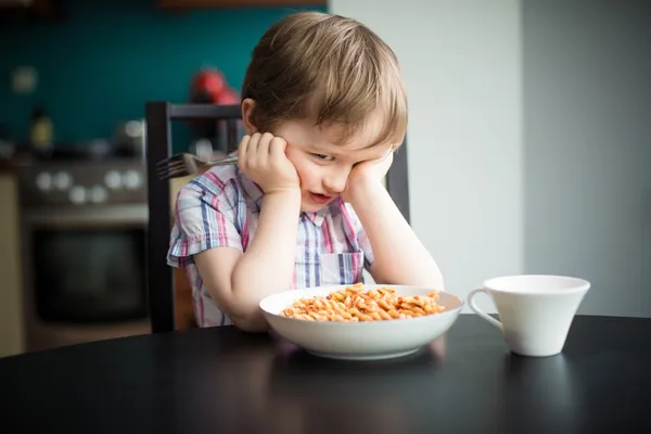 Beleidigter kleiner Junge weigert sich, Essen zu essen Stockbild