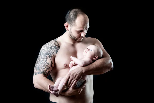 Muscular tattooed father holds on hands his newborn son — Stock Photo, Image