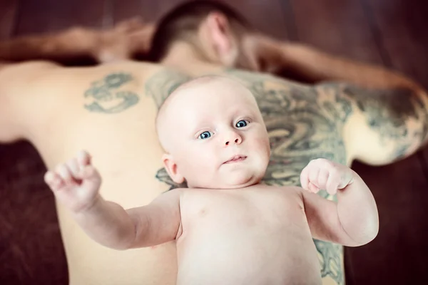 Nouveau-né couché sur son père tatoué dos musclé — Photo