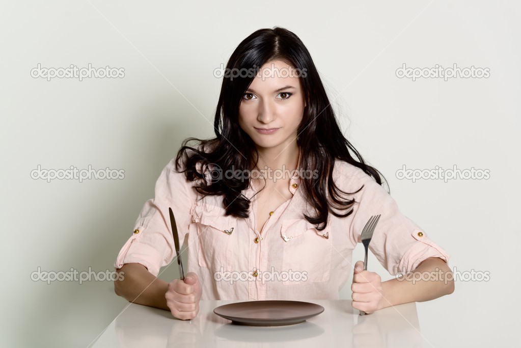 dissatisfied brunette woman waiting for a meal on an empty plate