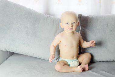 gri bir kanepe oturma odasında oturup bebek