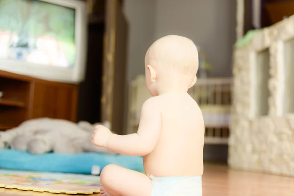 Meztelen baba, tévét ült a földön — Stock Fotó