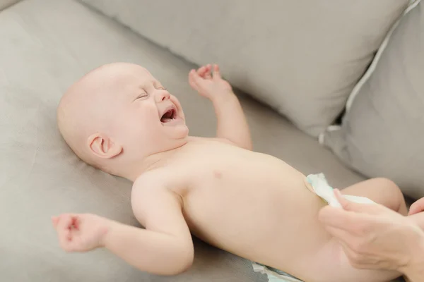 6-miesięcznego chłopca płacze, gdy matka jest zmiana jego pieluszka — Zdjęcie stockowe