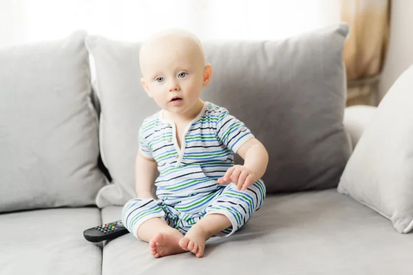 6 Monate Junge sitzt auf einem Sofa mit Fernbedienung für den Fernseher — Stockfoto