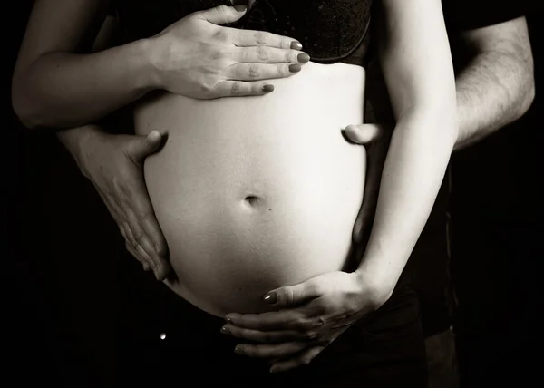 Father and mother holding hands on a pregnant belly — Stock Photo, Image