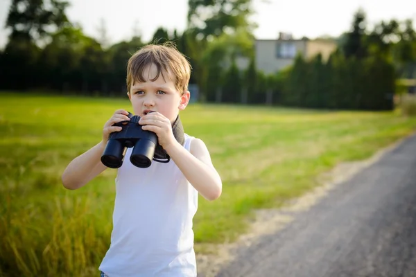 若い男の子は晴れた日に双眼鏡で遊んで. — ストック写真