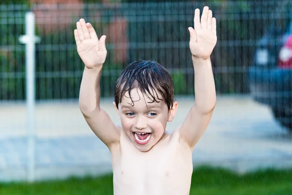 Happy little boy cools playing in the garden by rain — Stock Photo, Image