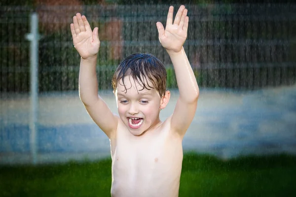 Menino alegre se divertindo enquanto toma banho no jardim — Fotografia de Stock