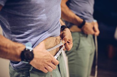 Göbeğini ölçmek için taksimetre kullanan adam.