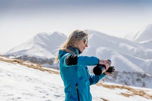 Γυναίκα ρίχνει και πίνοντας ζεστό τσάι ή καφέ από θερμός στο χειμερινό ορεινό μονοπάτι — Φωτογραφία Αρχείου