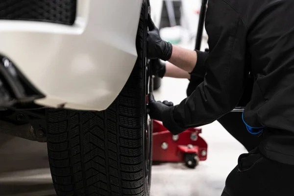Erkek araba servisi çalışanı arabanın tekerleğini değiştiriyor.. — Stok fotoğraf