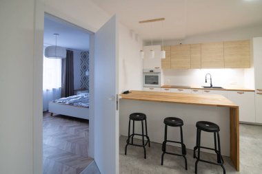 Modern bir mutfak tezgahı ve üç bar taburesi var.