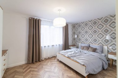 Geniş yataklı ve pencereli bir dairede modern bir yatak odası.