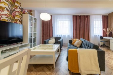 Oturma odası, kanepe yatağı, televizyon izleme alanı ve yemek masası.