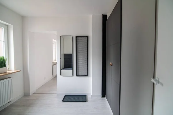 Hallway in a modern apartment with white walls, a mirror and a wardrobe