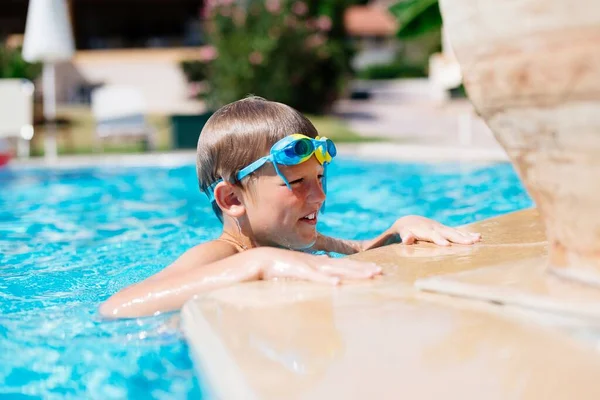 プールで泳いでいるとゴーグルをつけた少年が休んでいる ギリシャのコルフでの幸せな夏の休暇 — ストック写真