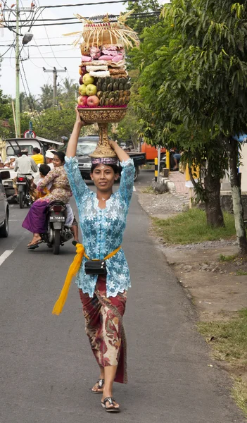 BALI, INDONESIA - 8 DE JUL: Una mujer lleva una cesta de frutas a —  Fotos de Stock