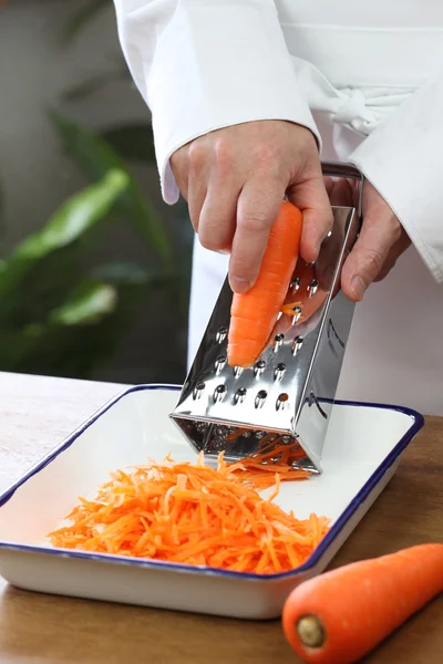Создание тертого салата из моркови, измельчение моркови — стоковое фото