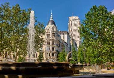 Madrid, Spain - May 10, 2022. Fountain of the Shell or the Birth of Water, with the Casa Gallardo building and the Madrid Tower in the background. Plaza de Espana square. Madrid, Spain.