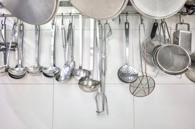 Kitchen Ladles, Cooking Skimmers and others Cookware hanging on the wall of a professional kitchen. clipart