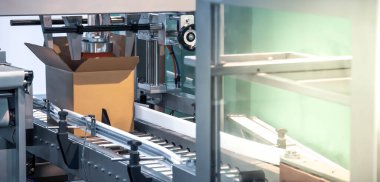 Automated carton, cardboard tape sealing machine. Industrial logistics warehouse.	