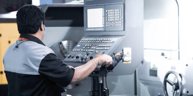 Makine teknisyeni atölyedeki CNC torna makinesini çalıştırıyor. Endüstriyel üretim.
