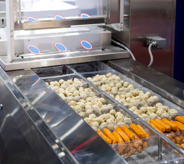 Упаковка мясошарика и колбасы на упаковочной машине для пищевой промышленности.