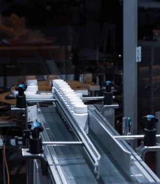 Kapsül dolum makinesindeki beyaz plastik şişe üretim hattında. İlaç endüstrisi..