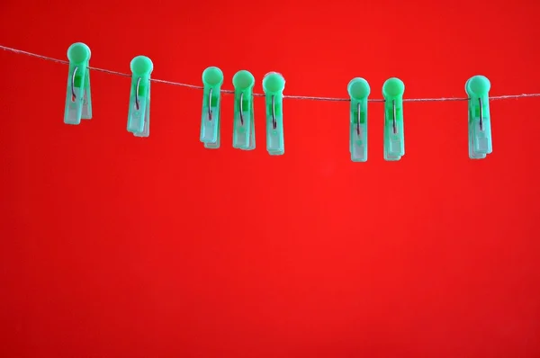 Plast klädnypor hängande på rep på en röd bakgrund — Stockfoto