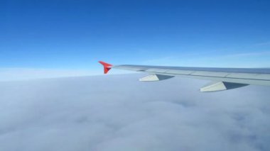 Gökyüzündeki bulutların üzerinde uçan uçağın kanatları