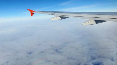 Gökyüzündeki bulutların üzerinde uçan uçağın kanatları