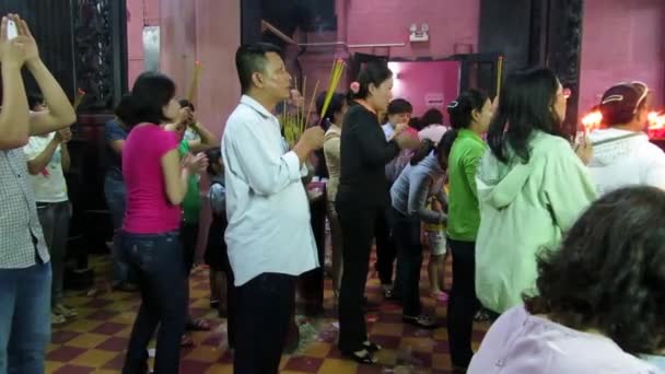 Creyentes no identificados orando y ofreciendo palitos de comida e incienso para los dioses en la pagoda del emperador vietnamita de Jade — Vídeos de Stock