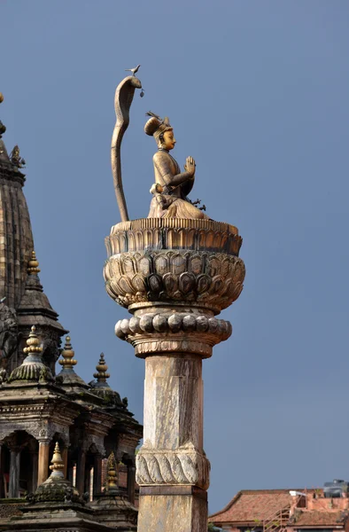 Estatua de bronce del rey Yoganarendra Malla, bajo la serpiente cobra, flanqueada por sus esposas, sobre la columna de piedra. Durbar cuadrado. Patan, Katmandú, Nepal —  Fotos de Stock