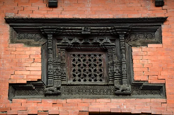 Vyřezávané dřevěné okno na cihlovou zeď. Káthmándú, Nepál — Stock fotografie